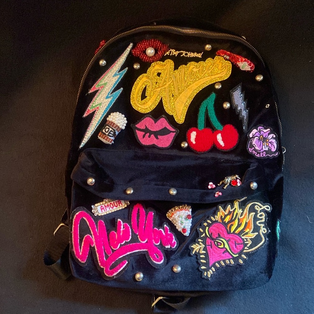 Black velvet Betsey Johnson book bag with multiple patches and studs.